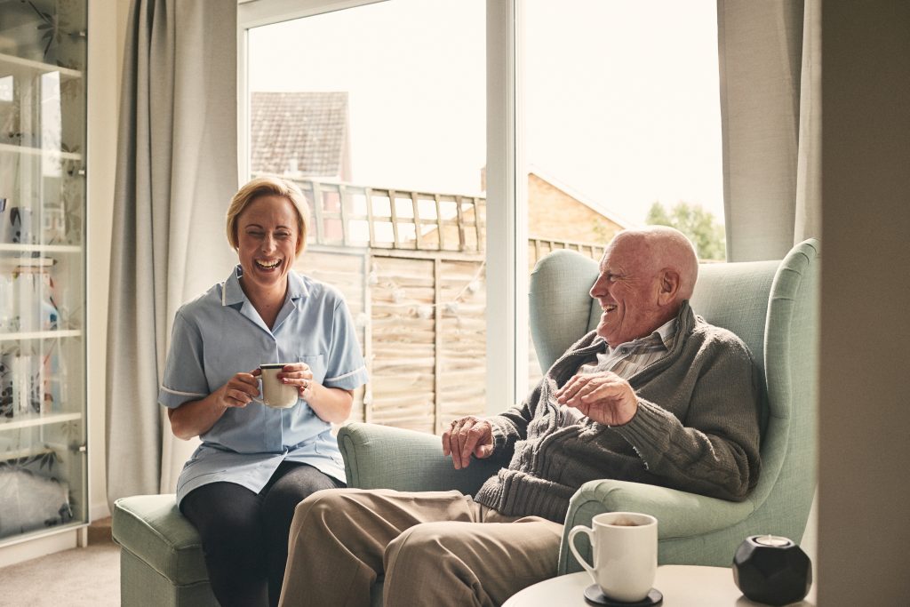 Carer enjoying coffee with smiling senior patient